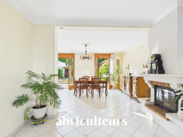 Intérieur d'une maison familiale avec salle à manger, cheminée et accès au jardin.