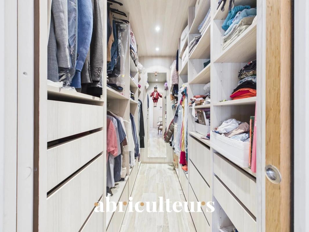 Dressing spacieux Intérieur d'un dressing spacieux avec rangements en bois clair et vêtements organisés.