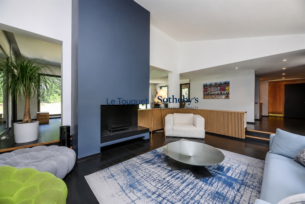 Intérieur d'une villa contemporaine avec salon, cheminée et accès à la terrasse.