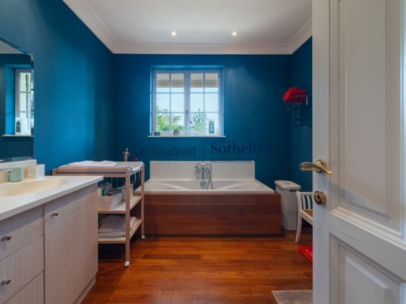 Salle de bain élégante avec baignoire et meuble en bois, murs peints en bleu.