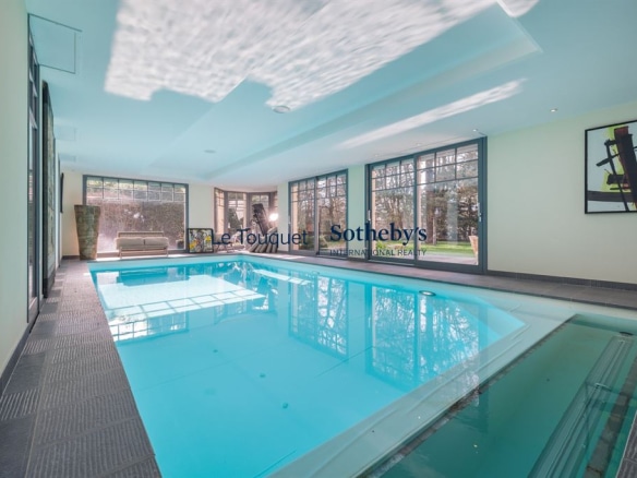 Intérieur d'une villa avec piscine, lumière naturelle, grandes fenêtres, décor moderne.