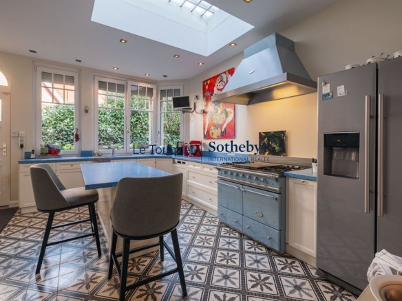 Cuisine moderne avec îlot central et fenêtres donnant sur un jardin.