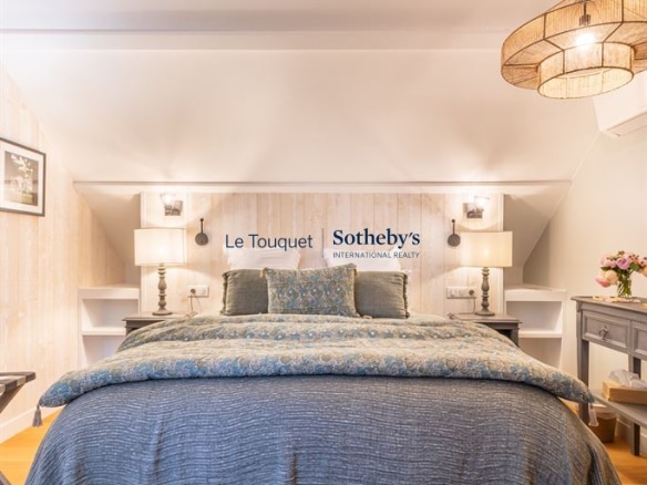 Chambre d'un gîte décoré avec un lit double et des lampes de chevet, murs clairs et tapis au sol.