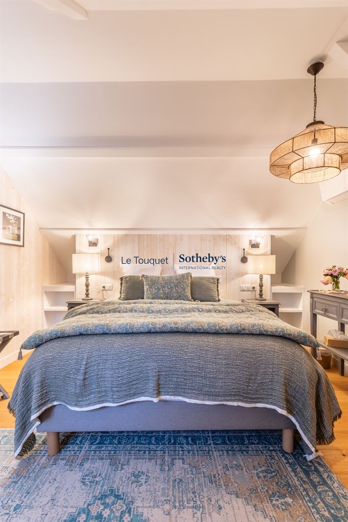 Chambre d'un gîte décoré avec un lit double et des lampes de chevet, murs clairs et tapis au sol.