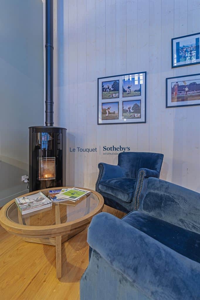 Salon d'un gîte décoré avec fauteuils et table basse, cheminée visible.
