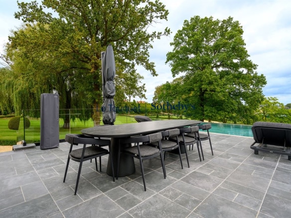 Modern terrace with outdoor furniture and infinity pool in a landscaped park.
