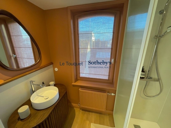 Modern bathroom with wooden sink and window in Le Touquet-Paris-Plage.