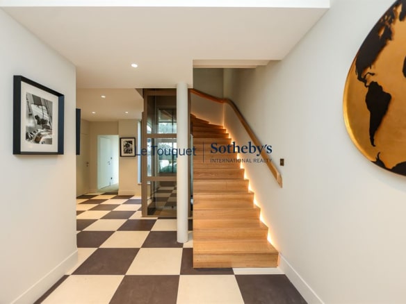 Interior of a modern villa with a wooden staircase and light-colored walls, in Le Touquet-Paris-Plage.