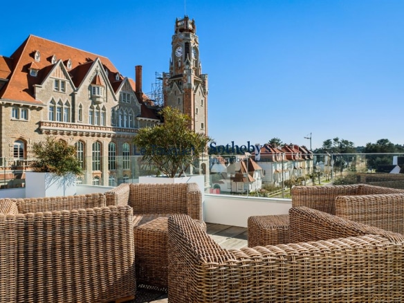 Terrasse avec mobilier en rotin et vue sur un bâtiment historique à Le Touquet-Paris-Plage.