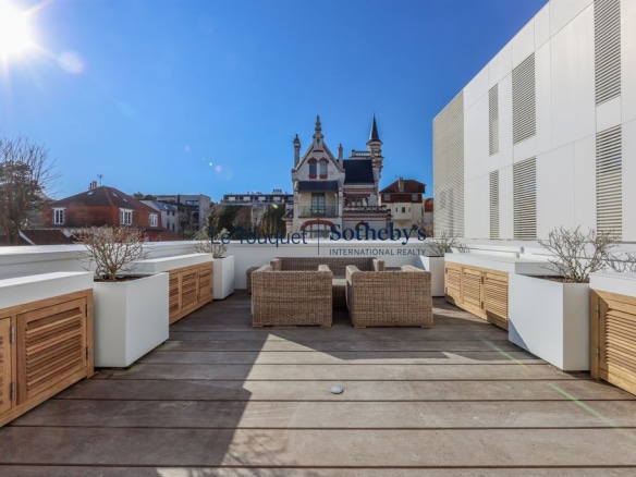 Terrasse d'une villa moderne avec mobilier extérieur, vue sur des bâtiments emblématiques à Le Touquet-Paris-Plage.