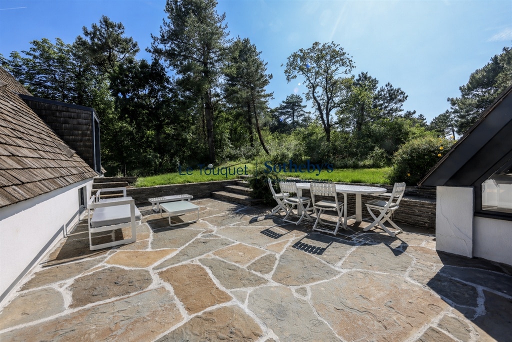 Stone terrace with garden furniture, surrounded by maritime pines and dunes in Le Touquet.