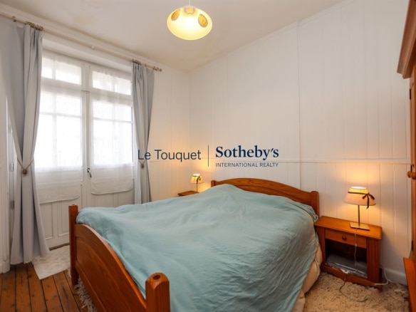 Chambre d'une villa familiale à Le Touquet-Paris-Plage, avec lit en bois et fenêtres lumineuses.