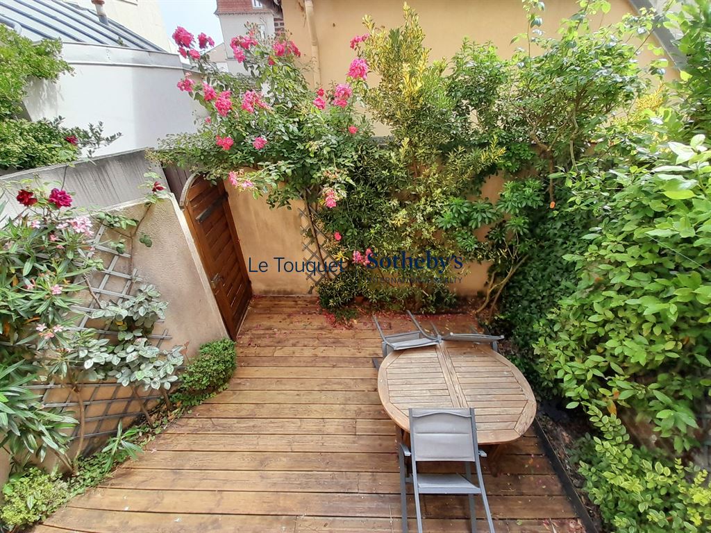 Jardin d'une villa avec terrasse en bois et fleurs à Le Touquet-Paris-Plage.