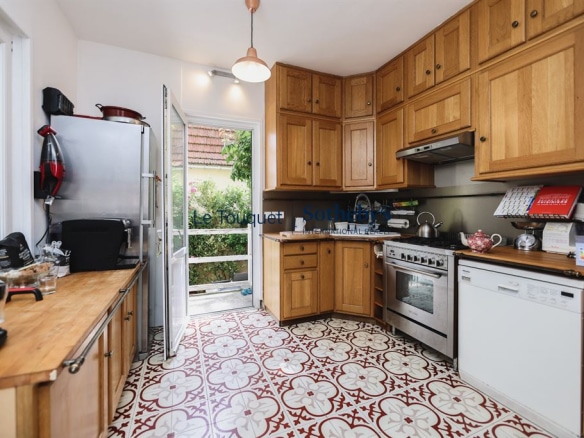 Cuisine en bois avec carrelage décoratif, fenêtre donnant sur l'extérieur.