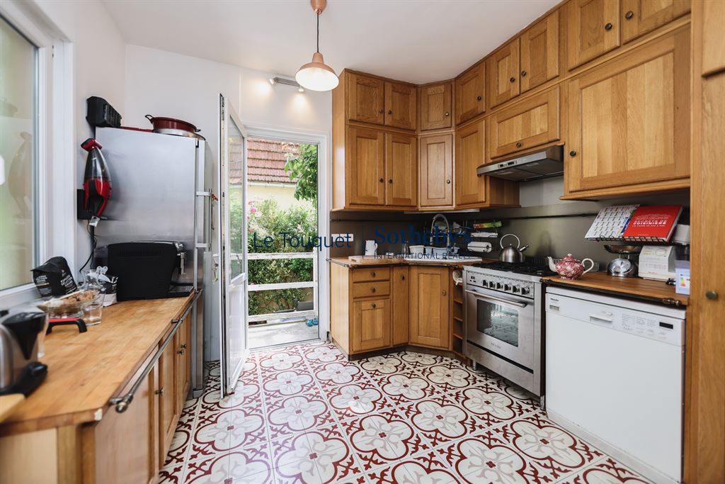 Cuisine en bois avec carrelage décoratif, fenêtre donnant sur l'extérieur.
