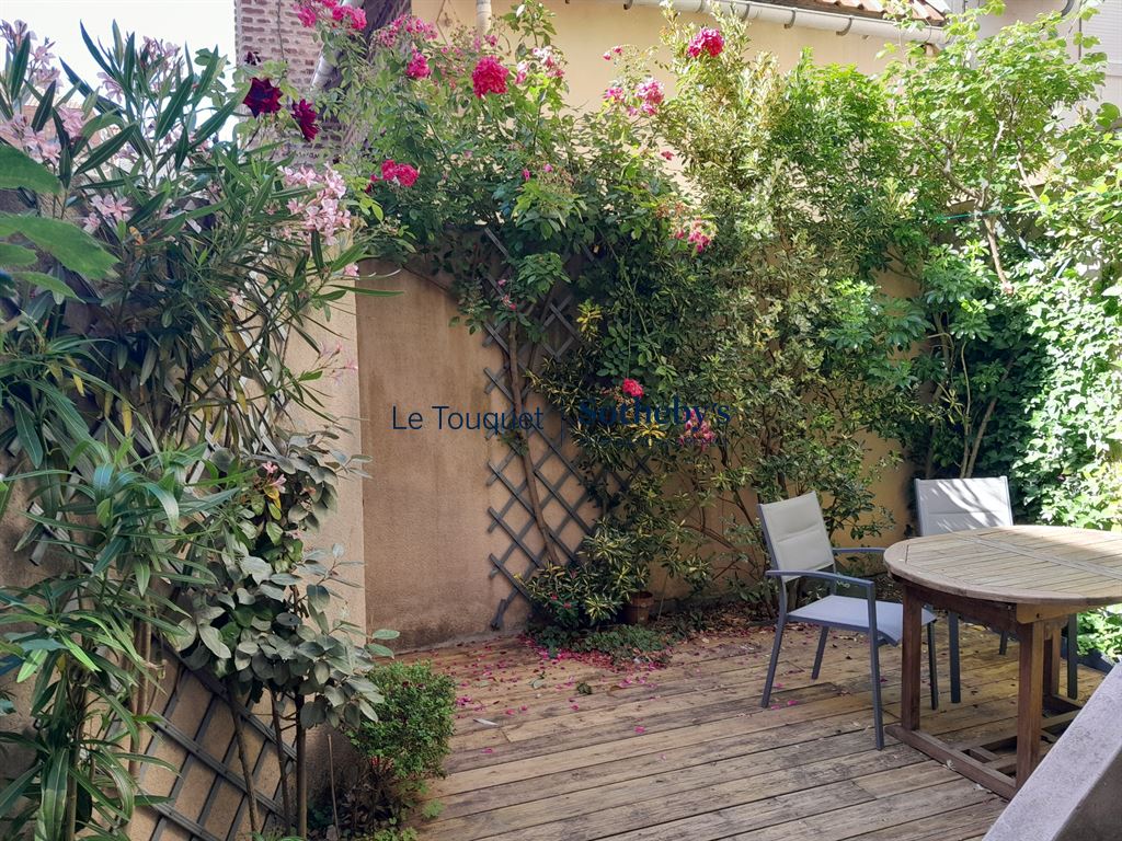 Jardin d'une villa avec des fleurs et une table en bois à Le Touquet-Paris-Plage.