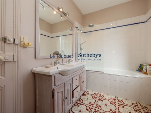 Salle de bain avec baignoire et lavabo, carrelage décoratif au sol.