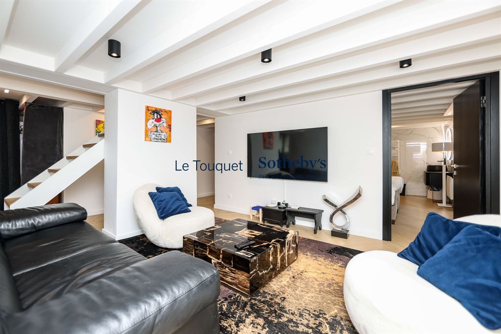 Interior of a contemporary duplex with living room, television and staircase.