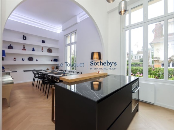 Interior of a contemporary duplex with kitchen and dining room, large windows and elegant decor.