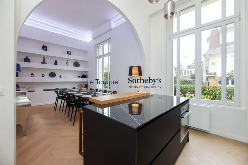 Interior of a contemporary duplex with kitchen and dining room, large windows and elegant decor.