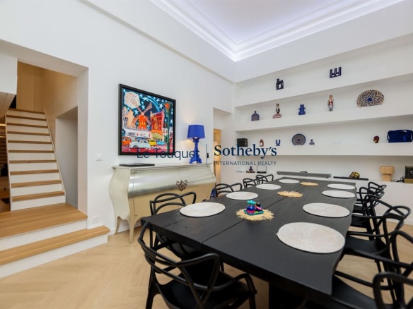 Interior of a contemporary duplex with a large dining table and a wooden staircase, Le Touquet-Paris-Plage.