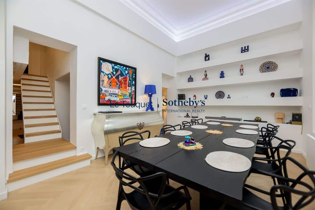 Interior of a contemporary duplex with a large dining table and a wooden staircase, Le Touquet-Paris-Plage.