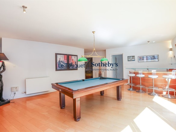 Interior of a contemporary villa with a pool table, bar and large, bright windows.
