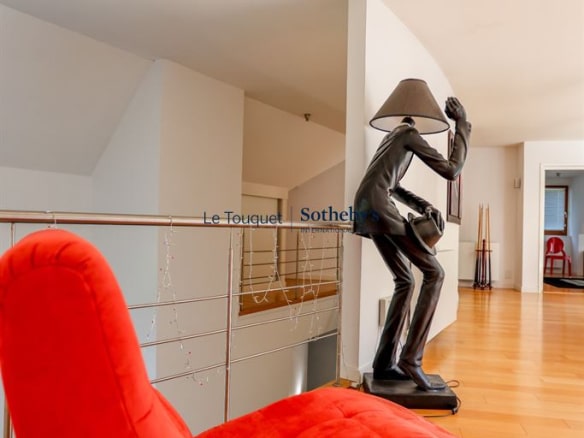 Interior of a contemporary villa with a red armchair and a metal sculpture.