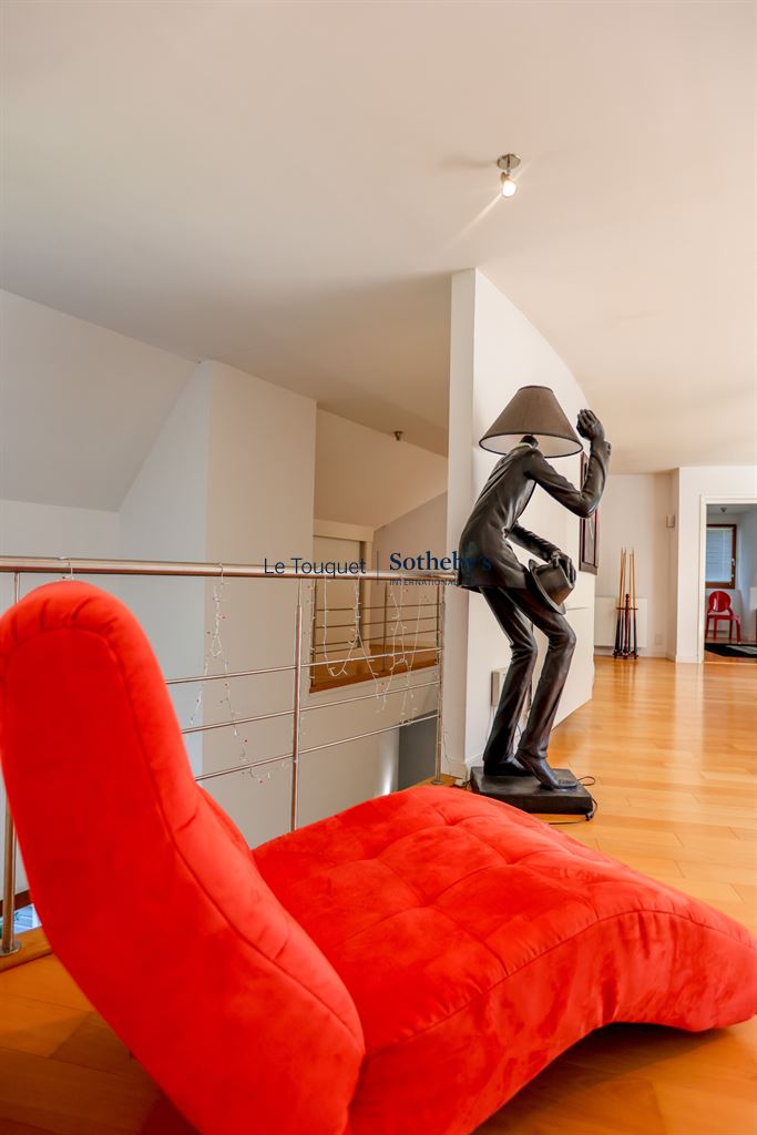 Interior of a contemporary villa with a red armchair and a metal sculpture.