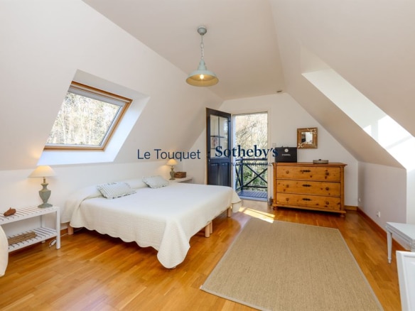 Bright room with a double bed, wooden furniture and access to a balcony.