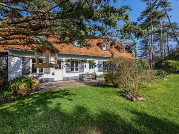 Flemish longhouse with garden in Hardelot Plage, surrounded by trees.