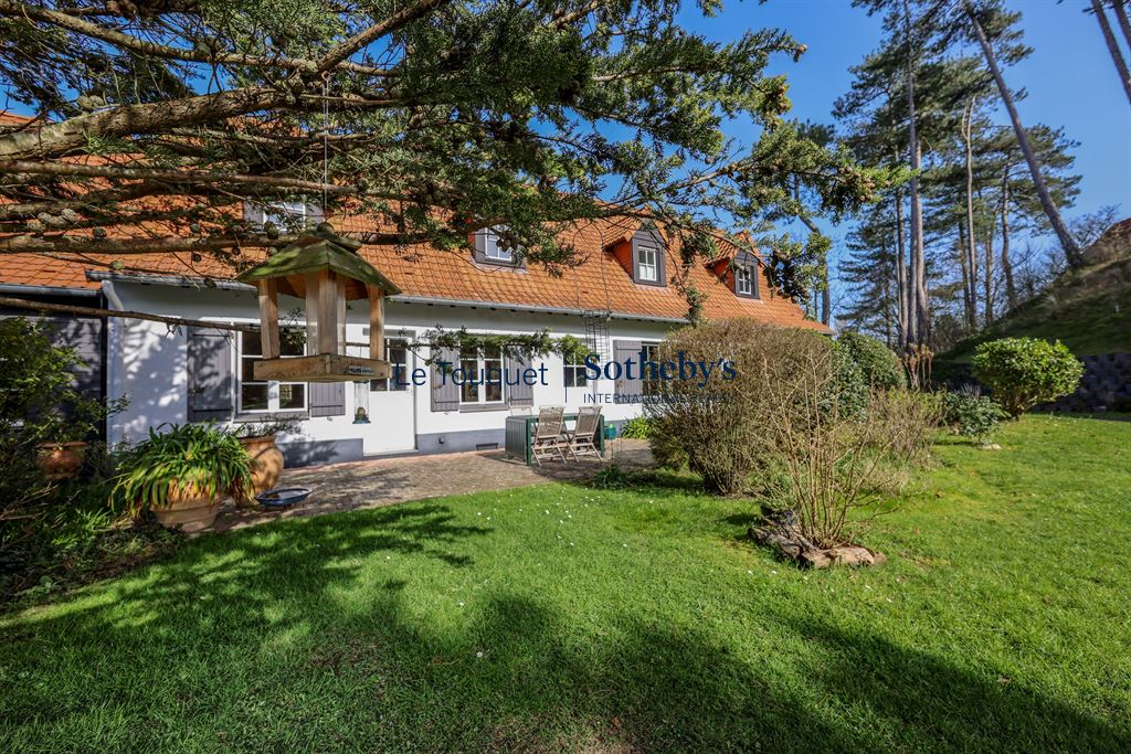 Flemish longhouse with garden in Hardelot Plage, surrounded by trees.