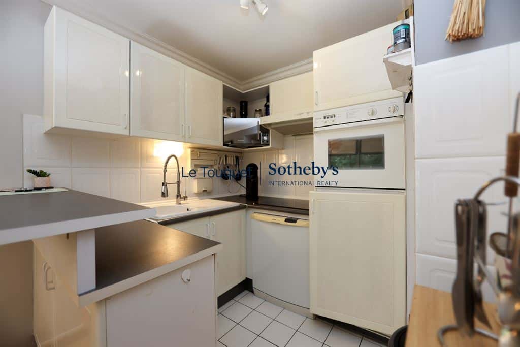 Equipped kitchen in a 77 m² apartment in Le Touquet-Paris-Plage, with light-colored furniture and appliances.