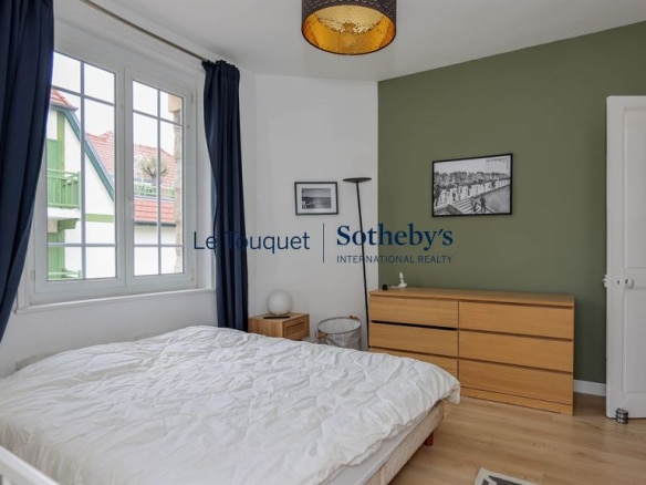 Bedroom in a renovated apartment with a double bed and light wood furniture, walls painted in green and white.