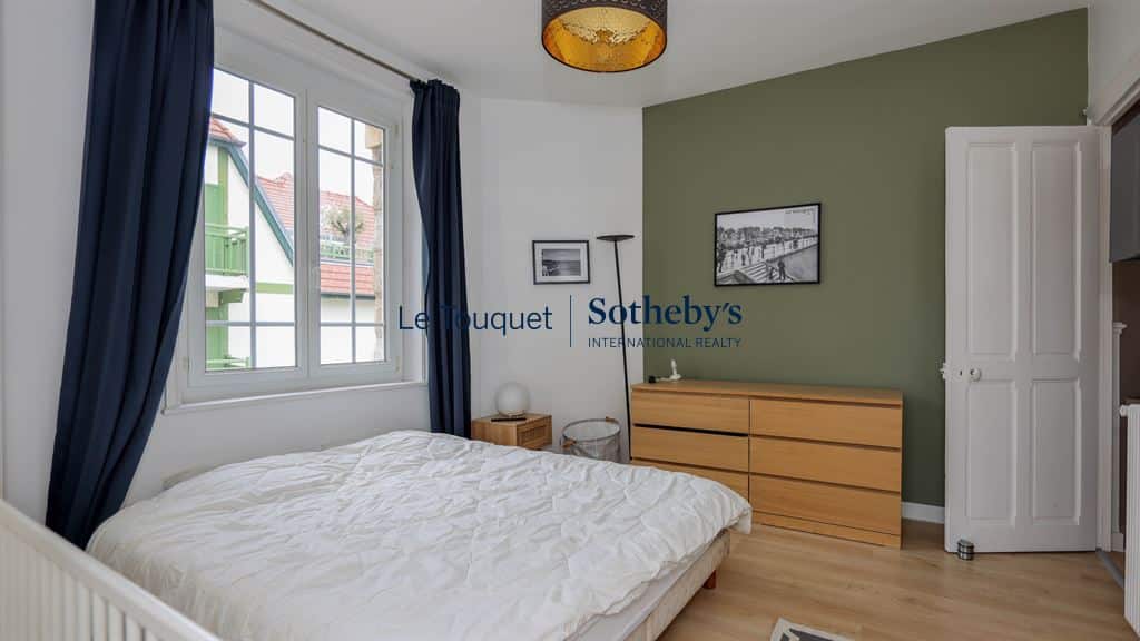 Bedroom in a renovated apartment with a double bed and light wood furniture, walls painted in green and white.