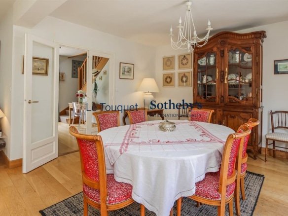 Dining room of a family villa in Le Touquet-Paris-Plage, with a round table and rattan chairs.