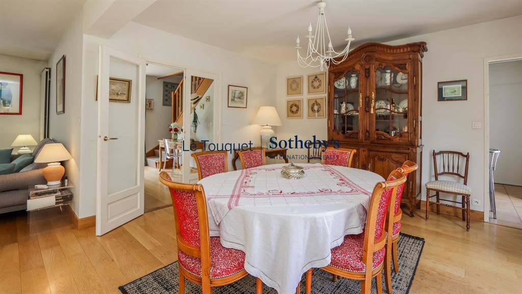Dining room of a family villa in Le Touquet-Paris-Plage, with a round table and rattan chairs.