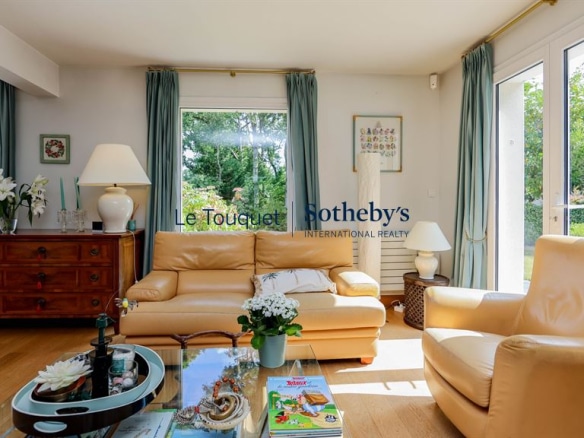 Interior of a family villa with a bright living room and windows overlooking the garden.