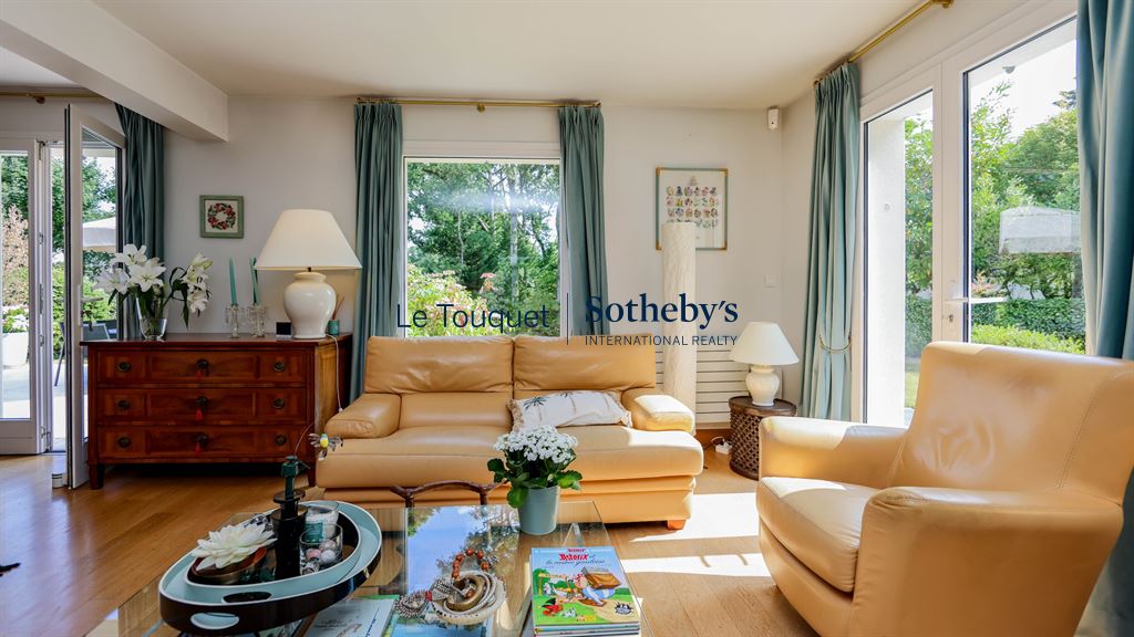 Interior of a family villa with a bright living room and windows overlooking the garden.
