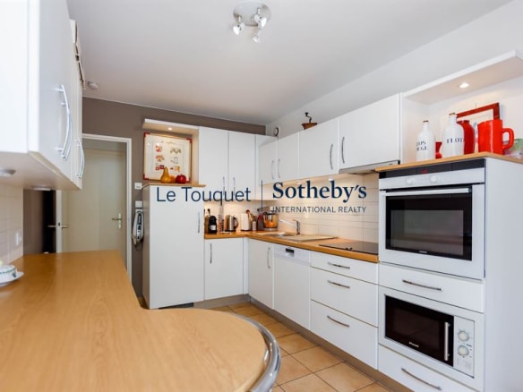 Modern kitchen in a family villa in Le Touquet-Paris-Plage, with integrated appliances and wooden worktop.