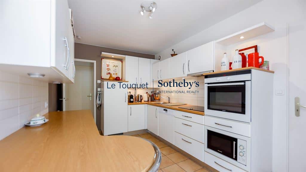 Modern kitchen in a family villa in Le Touquet-Paris-Plage, with integrated appliances and wooden worktop.