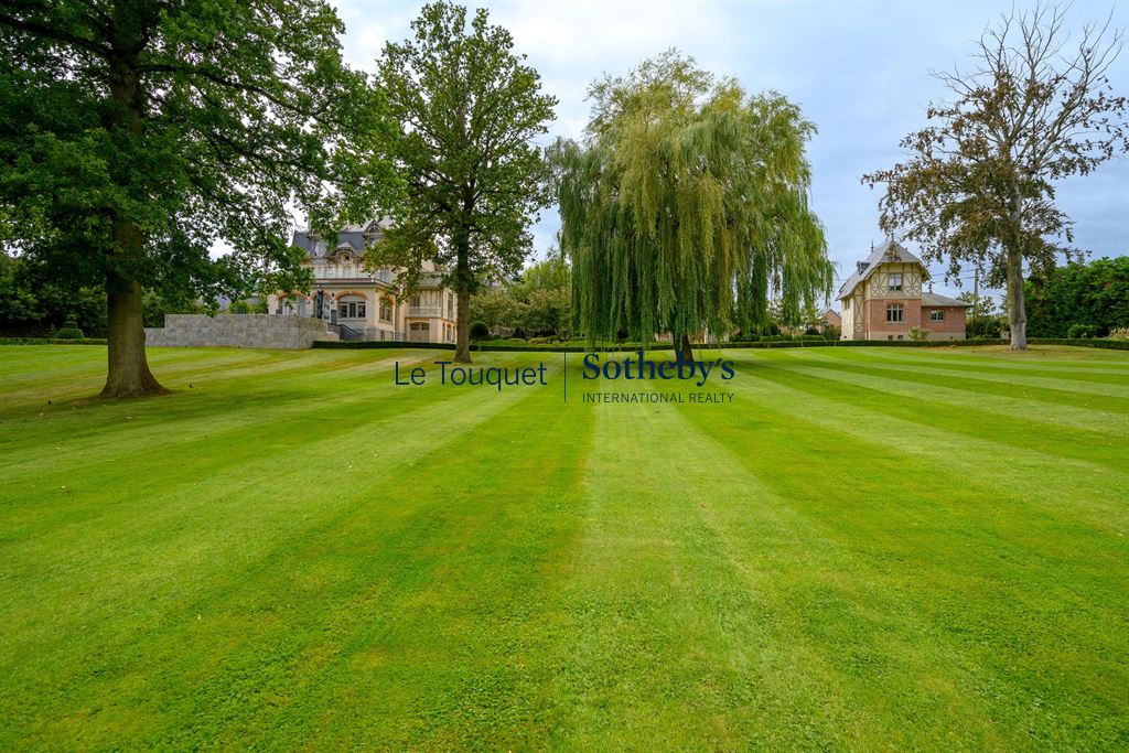 Hôtel particulier du XIXème à Mérignies Vue d'un hôtel particulier du XIXème siècle dans un parc paysagé avec pelouse et arbres.