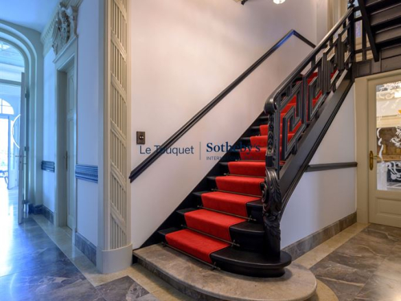 Escalier avec rampe en fer forgé et moquette rouge dans un hôtel particulier du XIXème siècle à Mérignies.