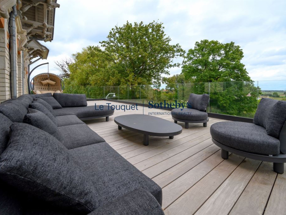 Terrasse avec mobilier moderne et vue sur un parc verdoyant.