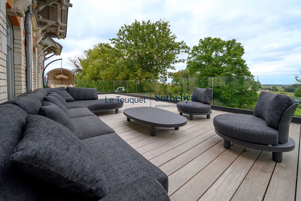 Terrasse d’un hôtel particulier à Mérignies Terrasse avec mobilier moderne et vue sur un parc verdoyant.