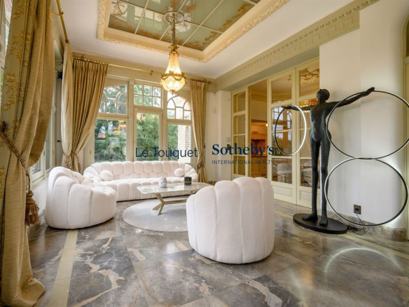 Intérieur d'un salon élégant avec canapé blanc, sculpture moderne et grandes fenêtres.