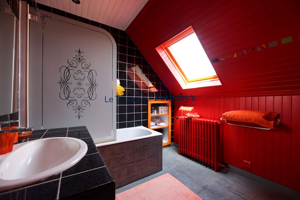 Salle de bain d’une villa à Wimereux Salle de bain moderne avec baignoire, lavabo et décor rouge vif.