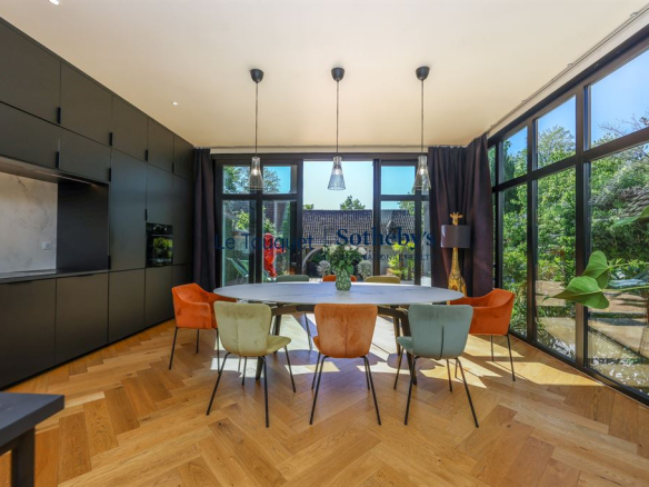 Salle à manger moderne avec grandes fenêtres et mobilier coloré dans un hôtel particulier rénové.