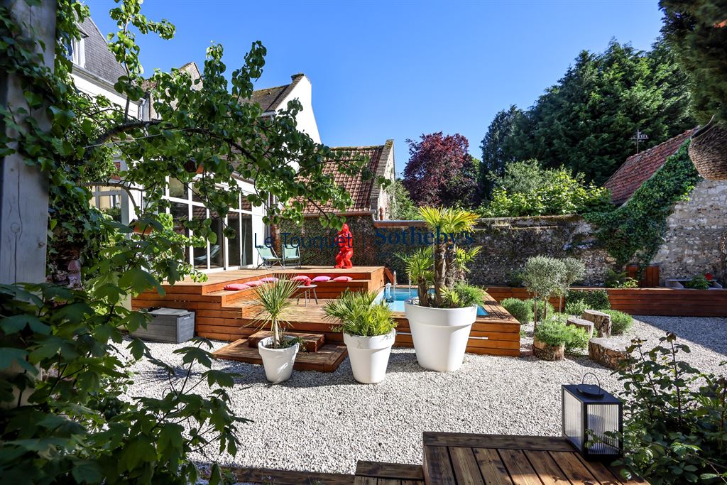 Jardin d’un hôtel particulier à Montreuil-sur-Mer Jardin d'un hôtel particulier du XVIIIème siècle à Montreuil-sur-Mer, avec des plantes et une terrasse en bois.