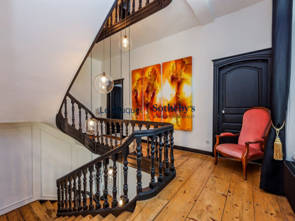 Escalier en bois avec lampes suspendues et fauteuil rouge dans un hôtel particulier du XVIIIème siècle à Montreuil-sur-Mer.